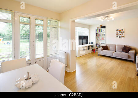 Ellington corte, Southgate. Soggiorno a pianta aperta con zona pranzo e un arredamento contemporaneo e un decor essenziale. Le porte del patio che conduce al cortile, giardino. Il pavimento in legno in tutta la stanza. Foto Stock