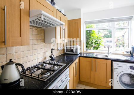 Ellington corte, Southgate. Pulire la cucina moderna con ripiani nero e armadi di legno. Piano cottura a gas ed elettrodomestici di acciaio inossidabile. Foto Stock