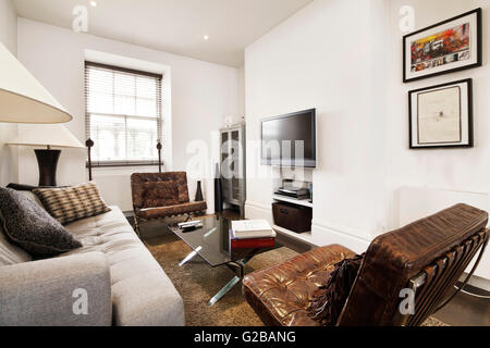 Walden House, Marylebone High Street. Vista ravvicinata di un soggiorno con la metà di secolo sedie e divani. Tv a schermo piatto su parete. Foto Stock