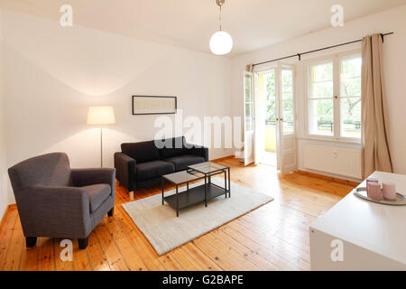 Wisbyer Strasse 59. Soggiorno moderno con minimo, dai toni neutri mobili e decorazioni. Stampa incorniciata appesa sopra il lettino. Ampia finestra e pavimento e lampade da soffitto. Foto Stock