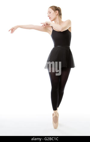 Lunghezza completa studio shot di una bellissima ballerina, en pointe, vestito in un tutto nero danza tuta con le braccia sollevate al Foto Stock