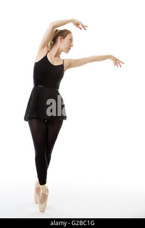 Lunghezza completa studio shot di una bellissima ballerina, en pointe, vestito in un tutto nero danza tuta con le braccia sollevate al Foto Stock