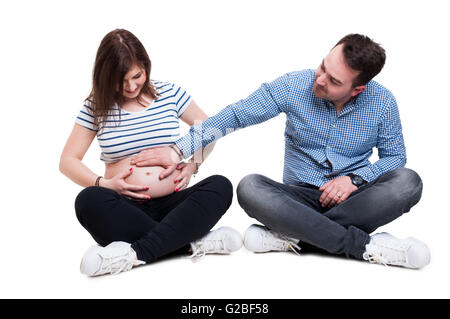 Attenzione marito tenendo la mano sulla sua moglie incinta pancia come coppia felice e il concetto di famiglia isolato su sfondo bianco Foto Stock