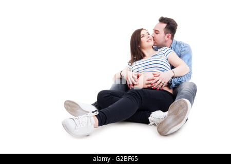 Futuro padre baciare sua moglie incinta sulla guancia e cercando felice insieme su sfondo bianco con area pubblicitaria Foto Stock