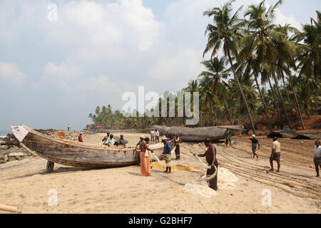 Gruppo di pescatori ordinamento le loro reti sulla spiaggia, Varkala Kerala, India Foto Stock