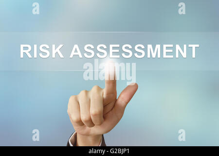 Business mano spingendo la valutazione del rischio pulsante sullo sfondo sfocato Foto Stock