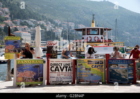 La gente di vendite vendita di gite in barca per i turisti dalle loro scrivanie sul porto di Dubrovnik Croazia Foto Stock