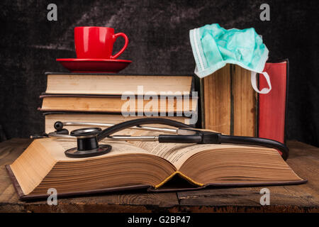 Uno stetoscopio sul libro aperto e caffè sulla pila di libri Foto Stock
