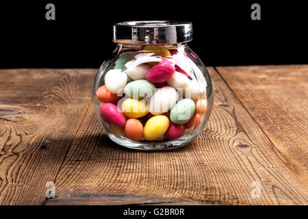 Il vasetto di vetro con colori caramella sul tavolo di legno Foto Stock