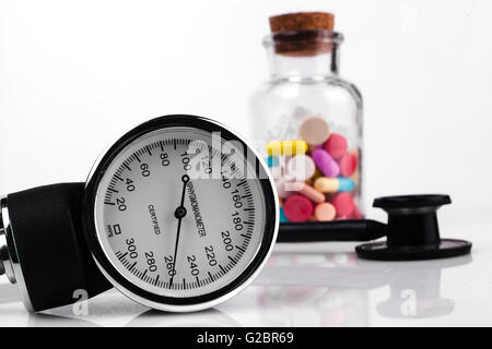 Pillole colorate in un vasetto con sfigmomanometro e stetoscopio nero Foto Stock