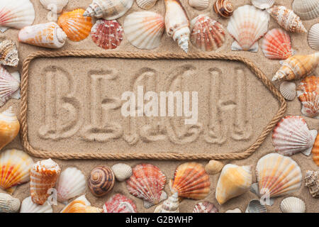 Puntatore a corda con una iscrizione Beach, con conchiglie di mare, sulla sabbia Foto Stock