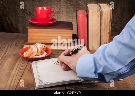 Vecchi libri sulla tavola di legno con il caffè e il notebook aperto Foto Stock