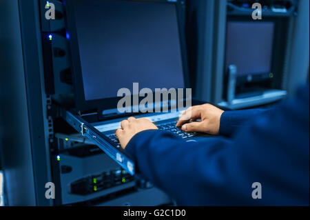 L'uomo fissare la rete di server in data center stanza . Foto Stock