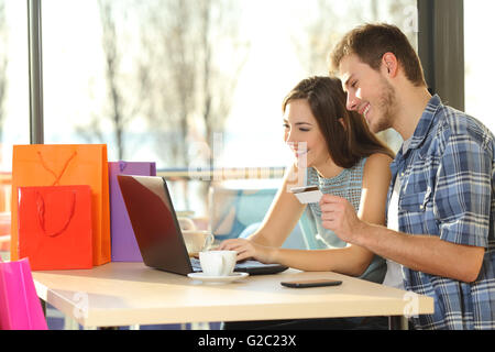 Paio di acquisti online con carta di credito e il laptop con le borse della spesa in un coffee shop Foto Stock