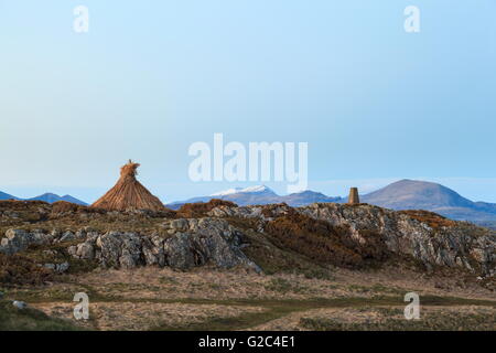 Un ri-costruito roundhouse sorge in prossimità di un punto di innesco sulla penna ychain un promontorio sulla Lleyn Peninsula, con un Snow capped Snowdon nel th Foto Stock