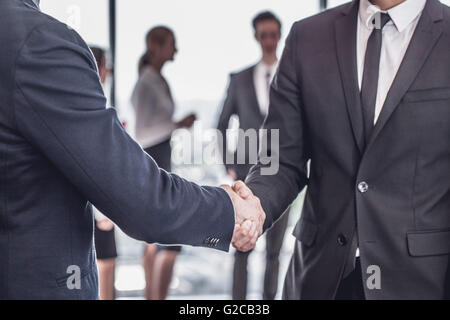 Stretta di mano nella parte anteriore del business team di persone in ufficio Foto Stock