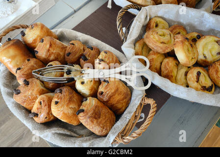 Visualizzazione dei prodotti di pasticceria francese compresi pain au chocolat o panini al cioccolato e pain au uvetta o focacce di ribes in cesti di pane Foto Stock