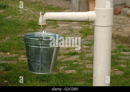 La vecchia pompa e la benna piena di acqua Foto Stock