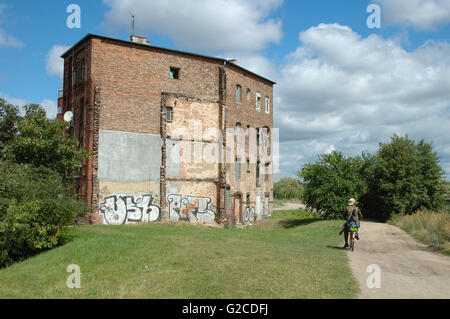 Poznan, Polonia - 13 Luglio 2014: ciclista non identificato e vecchio edificio devastato a Poznan, Polonia Foto Stock