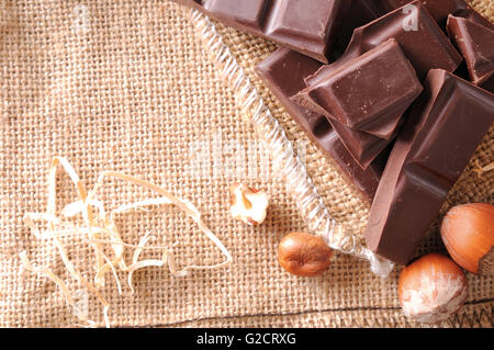 Cumulo di porzioni artigianale cioccolato sulla sacca di tela con nocciole con decorazione di paglia. Composizione orizzontale. Vista dall'alto. Foto Stock