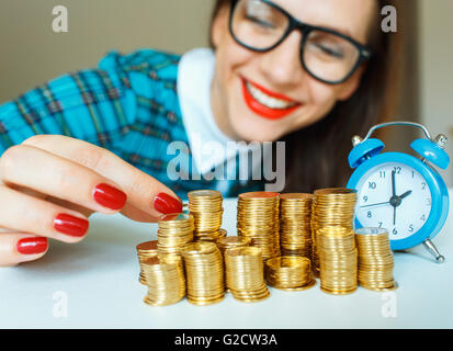 Salvataggio, donna sorridente di impilamento delle monete in oro in colonne Foto Stock