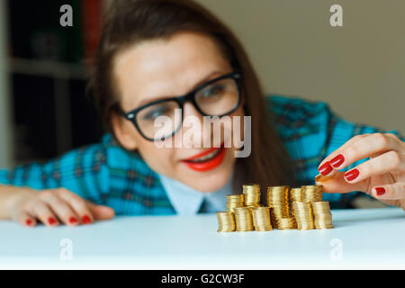 Salvataggio, donna sorridente di impilamento delle monete in oro in colonne Foto Stock
