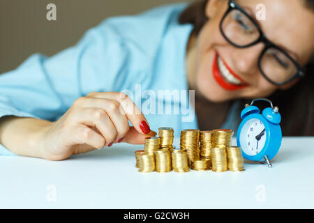 Salvataggio, donna sorridente di impilamento delle monete in oro in colonne Foto Stock
