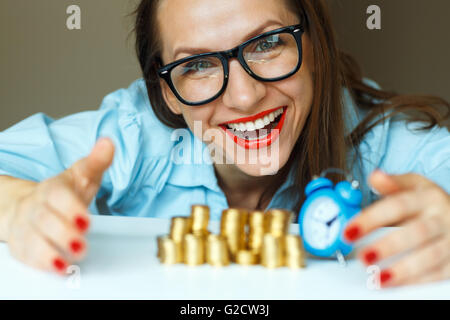 Salvataggio, donna sorridente di impilamento delle monete in oro in colonne Foto Stock