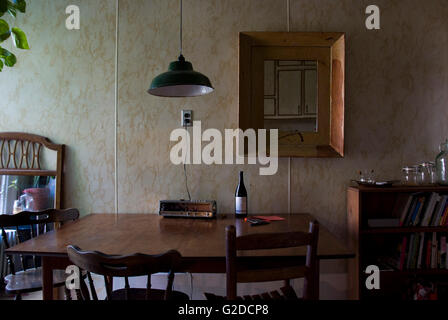 Vecchia cucina con tavolo in legno e sedie contro la parete in laminato Foto Stock