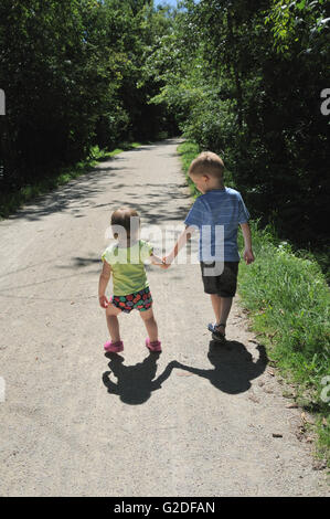 Ragazzo e ragazza tenendo le mani mentre camminavamo lungo il percorso Foto Stock