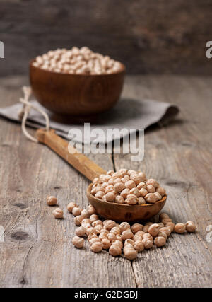 Ceci secchi in un cucchiaio di legno sul vecchio sfondo di legno Foto Stock
