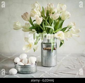 Natura morta con tulipani nel vecchio latte può e uova Foto Stock