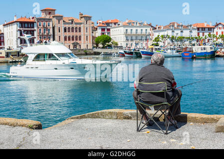 Pescatore pesca in Saint Jean de Luz - Ciboure porto di pesca con maison de Le Infante Joanoenia in background. La Francia. Foto Stock