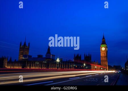 Palazzo di Westminster a Londra e il Big Ben di notte con il veicolo lasciando un sentiero lungo la strada con un cielo blu chiaro. Foto Stock