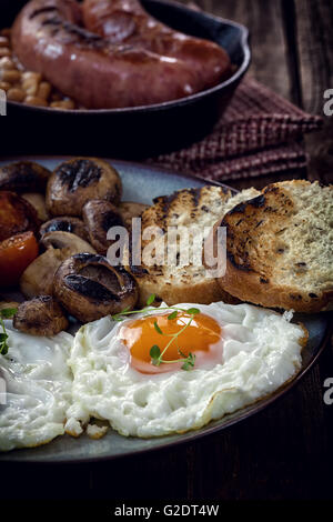 Prima colazione Inglese con uova, pomodori, funghi, pancetta, fagioli