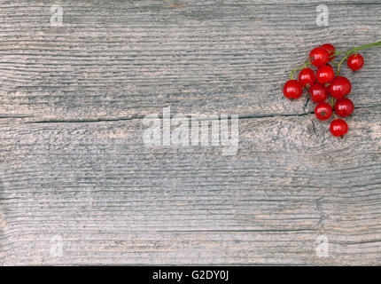 Ribes rosso in primo piano su un anziano tavola di legno, Plank. Texture, pattern nella scheda. Foto Stock