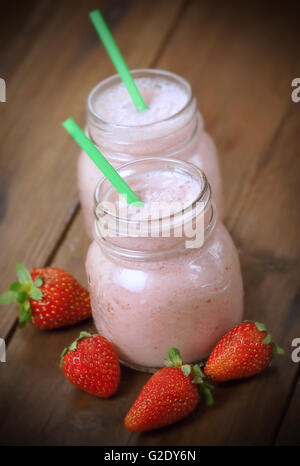 Frullato di fragole con paglia e tutta la fragola sul tavolo di legno Foto Stock