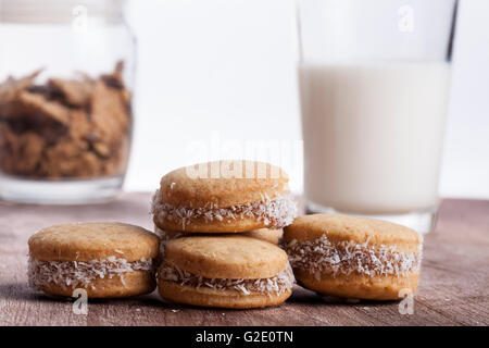 Piccolo giro cocnut cookie con latte vetro in bakcground sul piatto di legno Foto Stock
