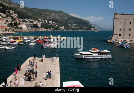 Porto vecchio di Dubrovnik Croazia i turisti si mescolano alla città vecchia Porto di Dubrovnik dove piccoli traghetti arrivano e partono Foto Stock