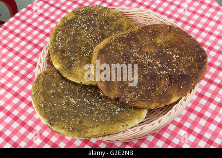 Pane Pita con zaatar medio verde erba orientale sulla tabella rossa Foto Stock