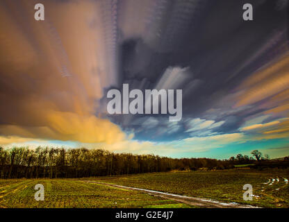 Il timelapse movimento delle nubi verso boschi attraverso un campo di colture Foto Stock