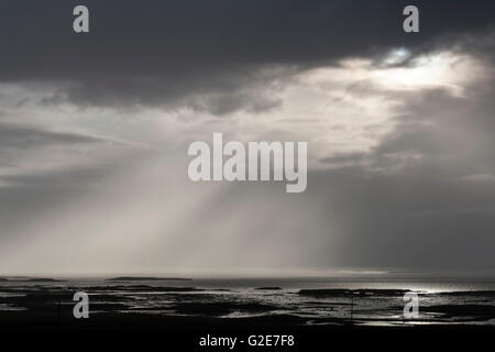 Cielo drammatico con raggi del sole proveniente attraverso le nubi sull'oceano Foto Stock