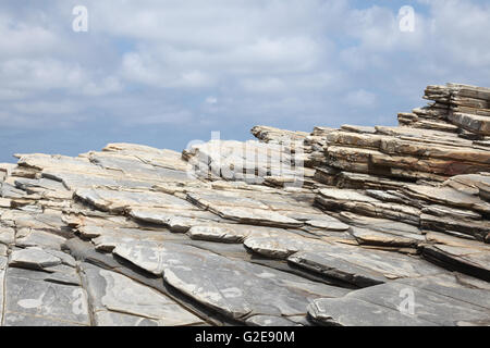 Le formazioni rocciose sulla spiaggia contro nuvoloso cielo blu Foto Stock