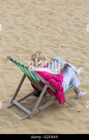 Bournemouth Dorset, Regno Unito il 30 maggio 2016. Donna seduta in sedia a sdraio leggendo il giornale a Bournemouth Beach su lunedì festivo su un nuvoloso giorno. Credito: Carolyn Jenkins/Alamy Live News Foto Stock