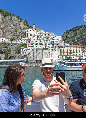 Un uomo con un attraente giovane donna prendendo un selfie su un giro in barca lungo la costa di Amalfi Italia Europa Foto Stock