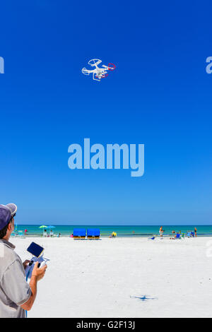 Un drone manovre pilota la gioia dei bastoni il controllore radio per un volo non-drone militare contro il cielo blu in spiaggia Foto Stock