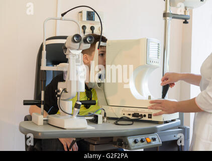 Il medico controlla il bambino gli occhi di fronte al dispositivo Foto Stock