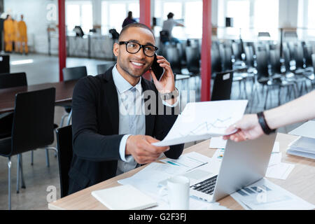 Sorridente bisnessman dando alle carte a qualcuno in ufficio Foto Stock