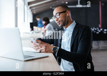 Imprenditore elegante digitando un messaggio utilizza lo smartphone in ufficio Foto Stock