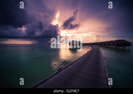 Incredibile sfondo astratto. Bel tramonto colori delle Maldive. Lungo pontile e lussuose ville overwater Foto Stock